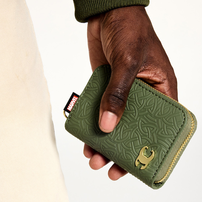 Close shot of a man's hand holding the Loungefly COLLECTIV Marvel Loki The ORGANIZR Accordion Wallet showing off the front, which is green and has a debossed pattern of Loki's intertwining snake symbol and his golden helmet in the lower corner.